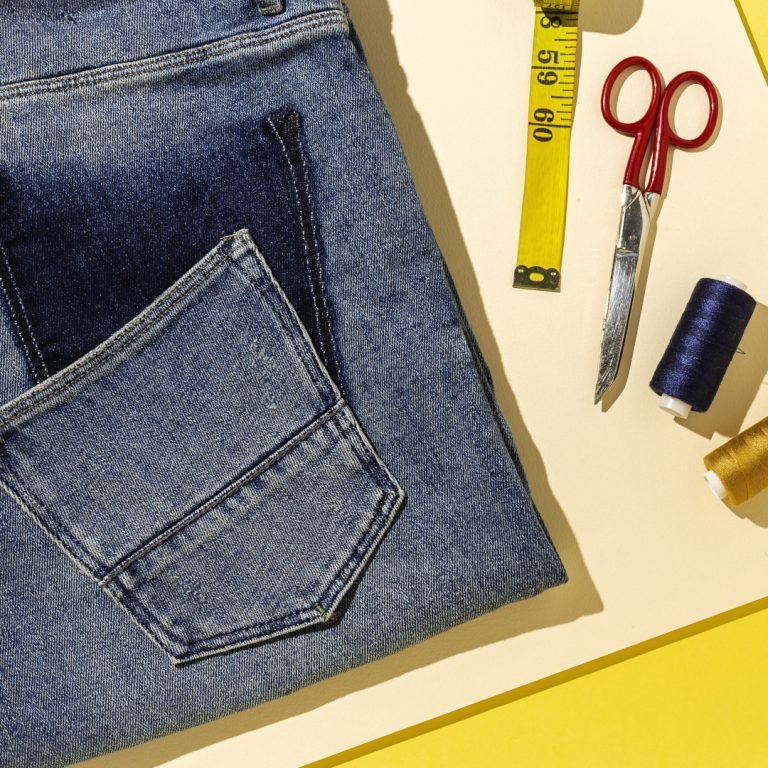 Handicraft, clothing repair. Ripped blue jeans sewing accessories with colorful background from above. Flat lay