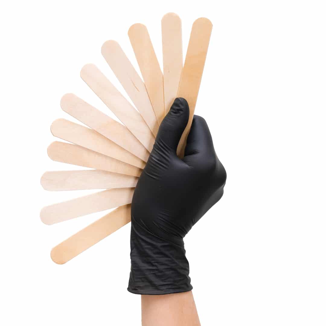 hand in a black glove holds wooden sticks for depilation on white isolated background. fan